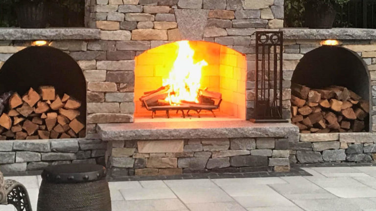 Stone outdoor fireplace with a lit fire
